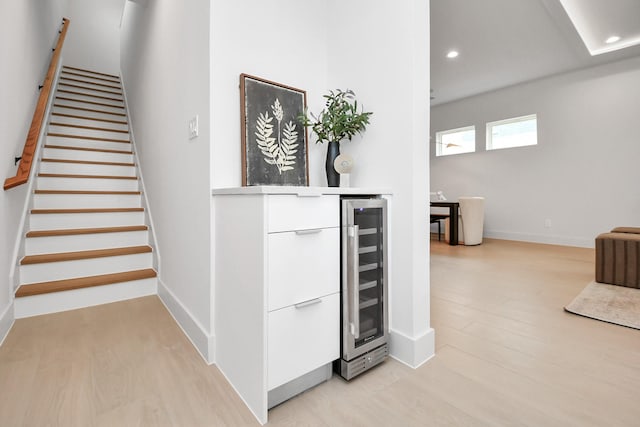 staircase featuring bar, hardwood / wood-style floors, and beverage cooler