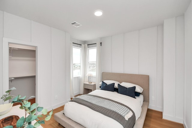 bedroom with a walk in closet and hardwood / wood-style flooring