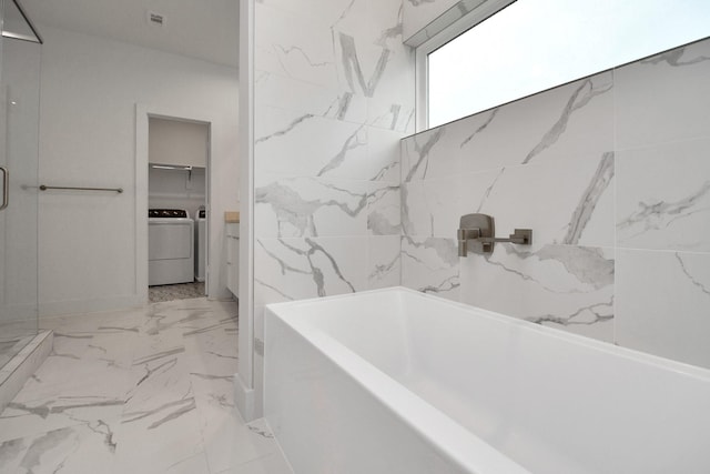 bathroom featuring separate shower and tub and separate washer and dryer