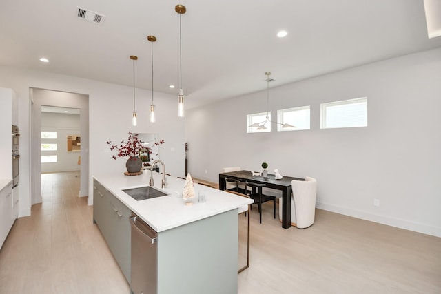 kitchen featuring pendant lighting, a wealth of natural light, a kitchen island with sink, and sink