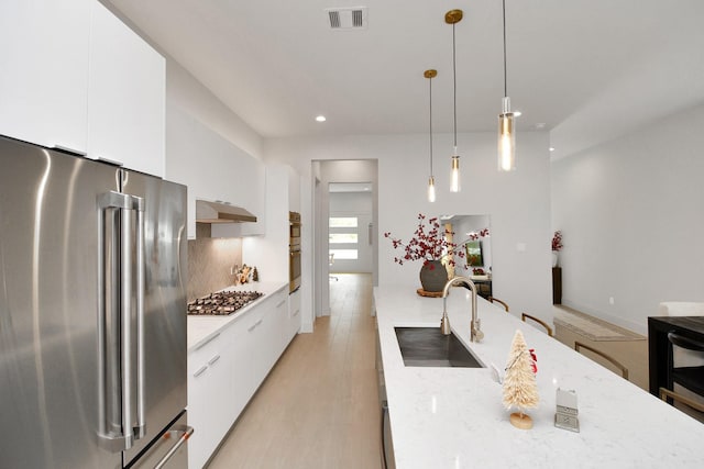 kitchen featuring sink, appliances with stainless steel finishes, decorative light fixtures, light hardwood / wood-style floors, and white cabinetry