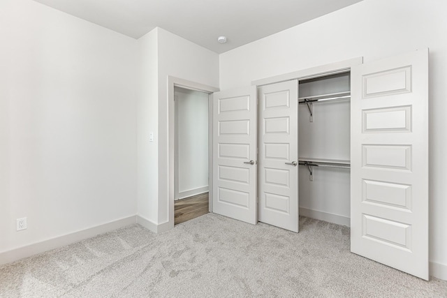 unfurnished bedroom featuring a closet and light colored carpet