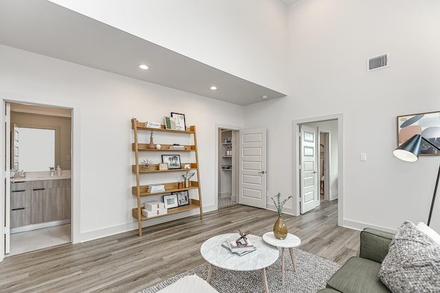 living room with light hardwood / wood-style floors, sink, and a high ceiling