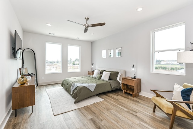 bedroom with multiple windows, ceiling fan, and light hardwood / wood-style floors