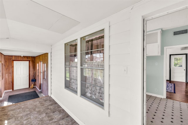 hallway with lofted ceiling and wooden walls