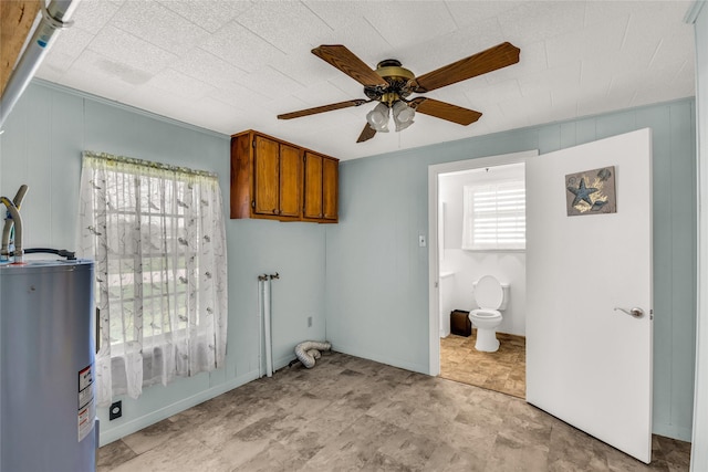 laundry room featuring a wealth of natural light, water heater, ceiling fan, and cabinets