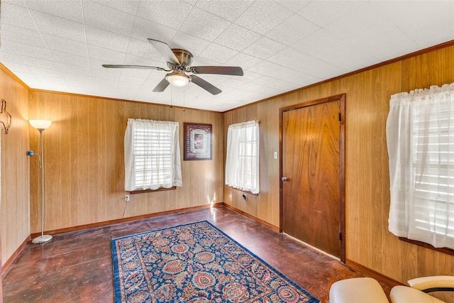 entryway with ceiling fan, ornamental molding, and wood walls