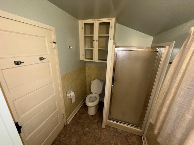 bathroom featuring toilet, an enclosed shower, tile walls, and vaulted ceiling