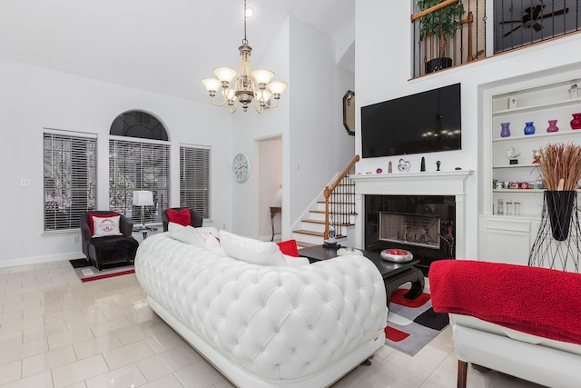 living room with an inviting chandelier, built in features, light tile patterned floors, and a tiled fireplace