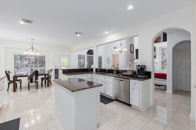 kitchen with dishwasher, sink, hanging light fixtures, dark stone countertops, and white cabinets