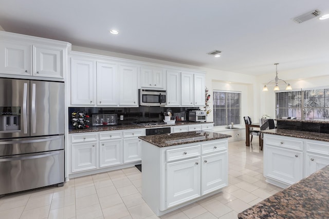 kitchen with a kitchen island, white cabinets, light tile patterned floors, and appliances with stainless steel finishes