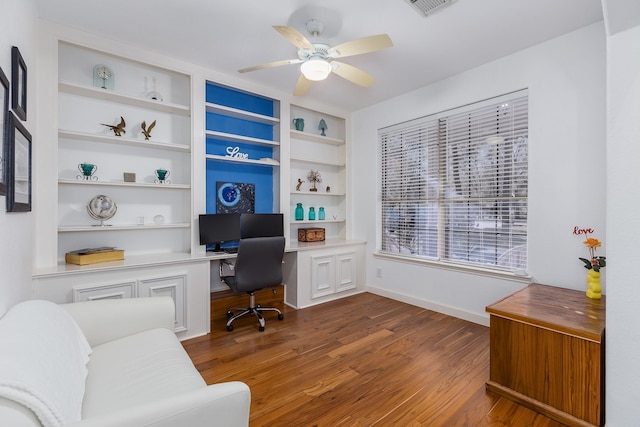 office area featuring dark hardwood / wood-style flooring, ceiling fan, built in features, and built in desk