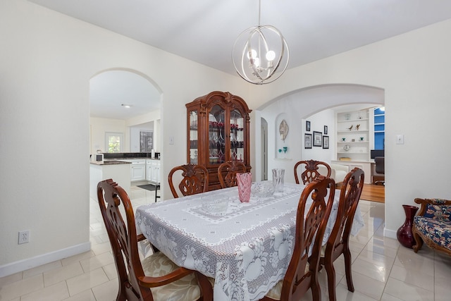 dining room with a chandelier, light tile patterned floors, and built in features