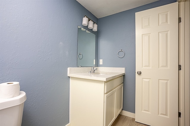 bathroom featuring vanity, hardwood / wood-style flooring, and toilet