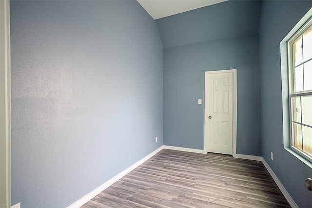 empty room with wood-type flooring and lofted ceiling