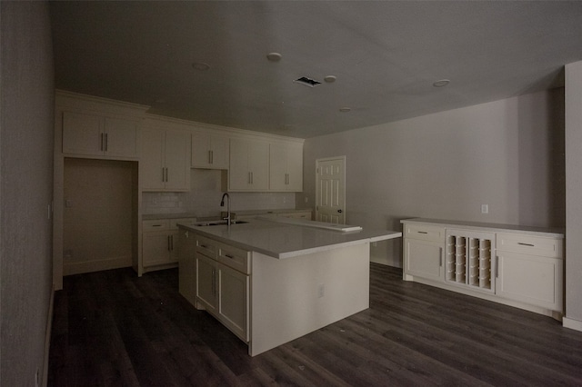 kitchen featuring dark hardwood / wood-style floors, white cabinetry, a kitchen island with sink, and sink