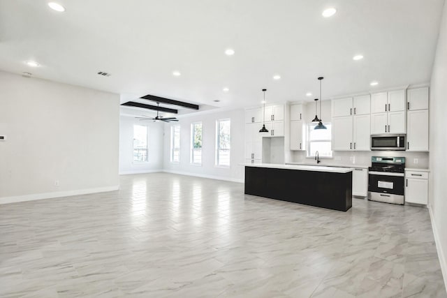 kitchen with a center island, white cabinets, hanging light fixtures, ceiling fan, and stainless steel appliances