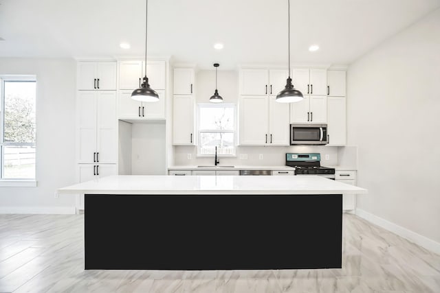 kitchen featuring a center island, white cabinets, black range with gas stovetop, sink, and hanging light fixtures