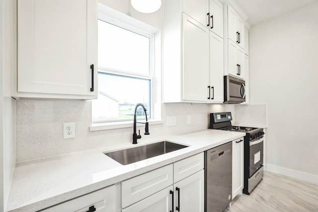 kitchen featuring light stone countertops, sink, tasteful backsplash, white cabinets, and appliances with stainless steel finishes