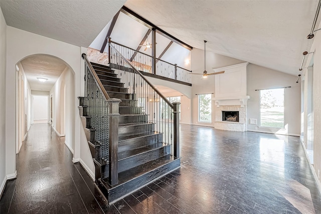 staircase with ceiling fan, a fireplace, hardwood / wood-style floors, and a textured ceiling