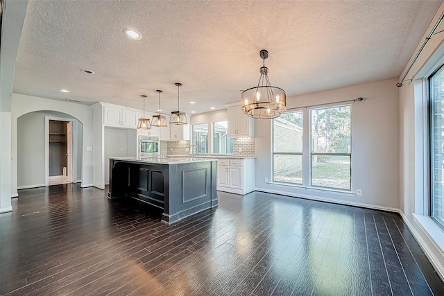 kitchen featuring white cabinets, backsplash, a large island, and stainless steel oven