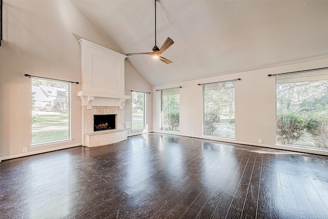 unfurnished living room featuring high vaulted ceiling, dark hardwood / wood-style floors, a stone fireplace, and ceiling fan