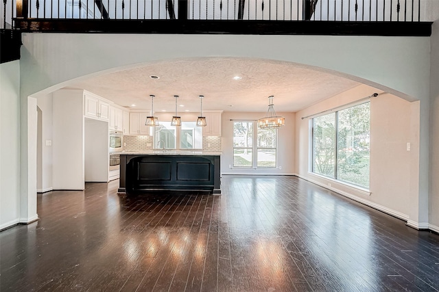 unfurnished living room featuring dark hardwood / wood-style flooring, a chandelier, and a textured ceiling