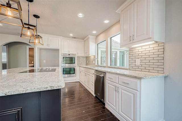 kitchen with white cabinetry, sink, stainless steel appliances, hanging light fixtures, and tasteful backsplash