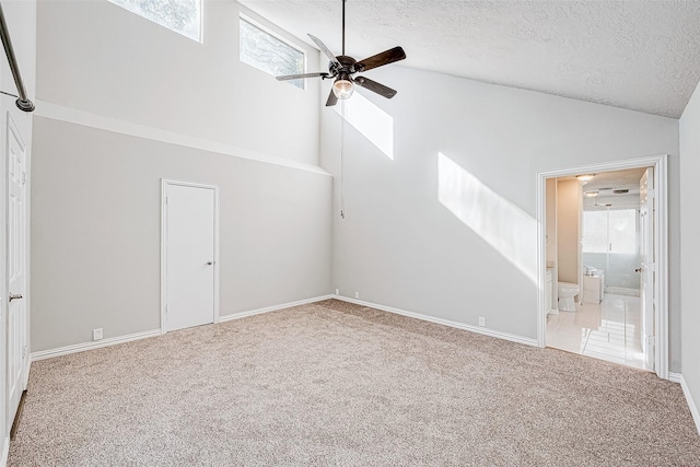 unfurnished living room featuring ceiling fan, carpet floors, a textured ceiling, and high vaulted ceiling