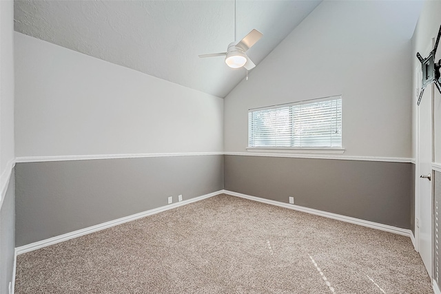 carpeted spare room featuring vaulted ceiling and ceiling fan