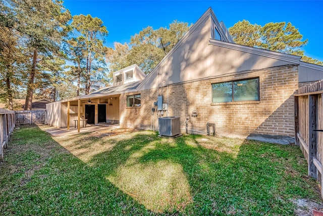 rear view of house featuring a lawn, cooling unit, and a patio