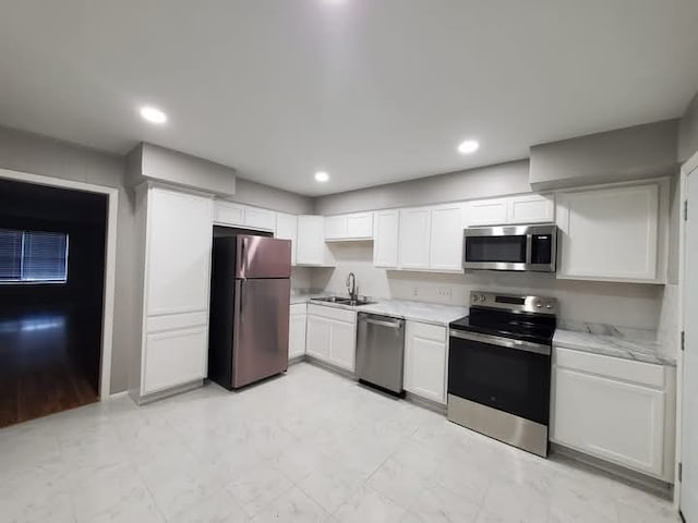 kitchen featuring white cabinets, sink, light stone countertops, and stainless steel appliances