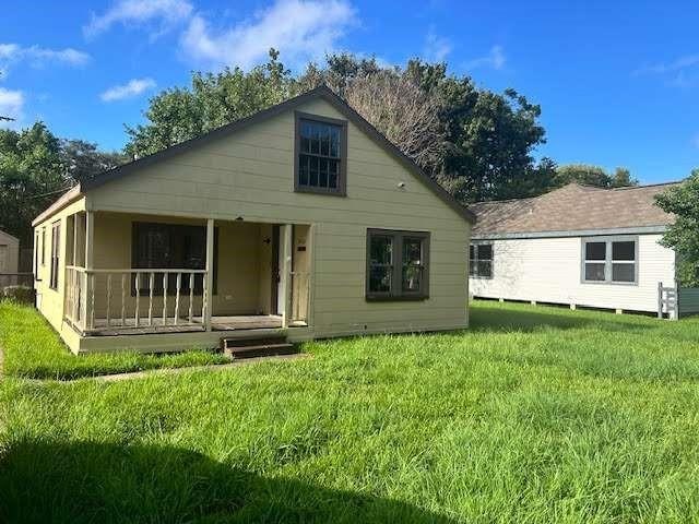 back of house featuring covered porch and a lawn