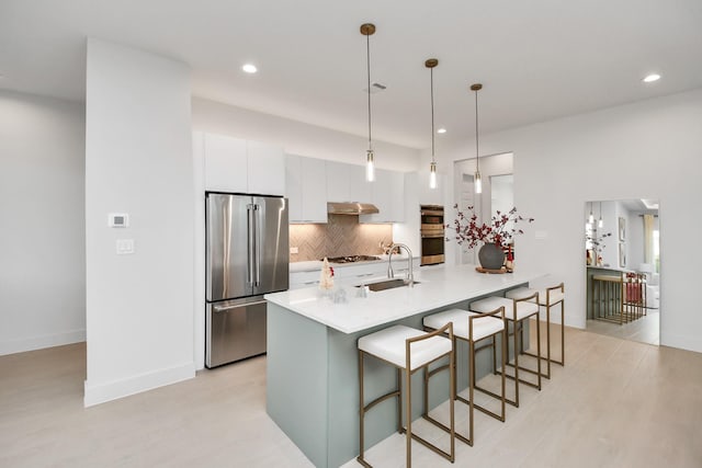 kitchen with sink, pendant lighting, stainless steel appliances, decorative backsplash, and white cabinets