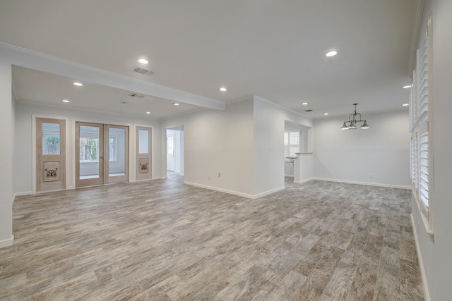 unfurnished living room with a wealth of natural light, a notable chandelier, and ornamental molding