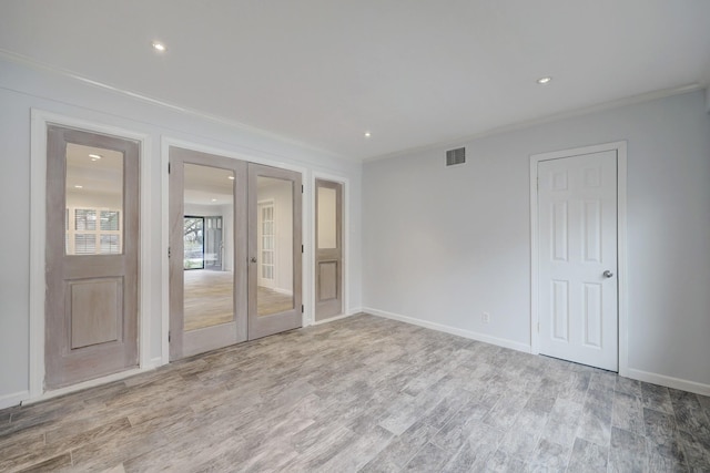 unfurnished room featuring french doors, light hardwood / wood-style flooring, and crown molding