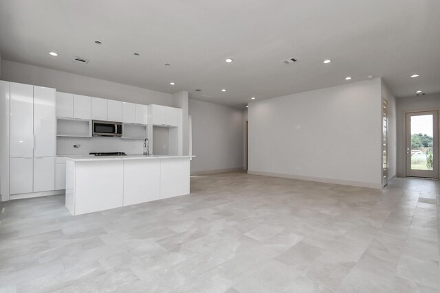 kitchen featuring sink, a kitchen island with sink, and white cabinets