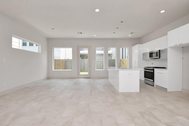 kitchen with sink, white cabinets, backsplash, a center island, and stainless steel appliances