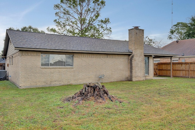 back of property with central AC unit, a yard, and an outdoor fire pit