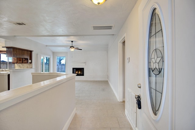 entryway featuring ceiling fan, light tile patterned floors, and a textured ceiling