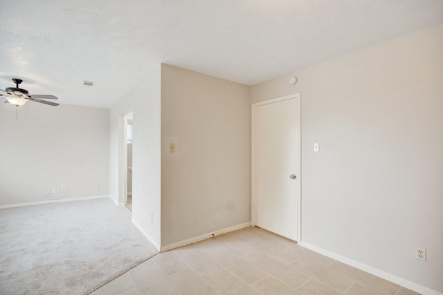 spare room featuring ceiling fan, a textured ceiling, and light carpet