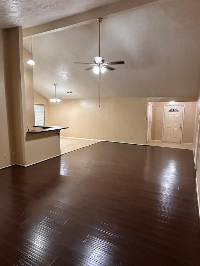 unfurnished living room featuring ceiling fan with notable chandelier, dark hardwood / wood-style flooring, and lofted ceiling