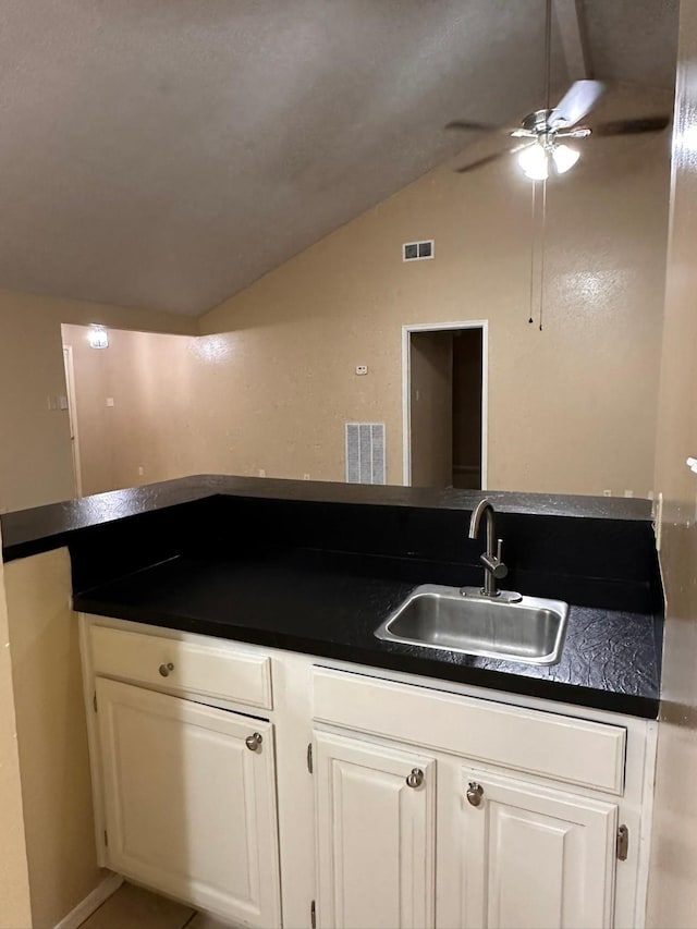 kitchen featuring ceiling fan, sink, tile patterned floors, lofted ceiling, and white cabinets