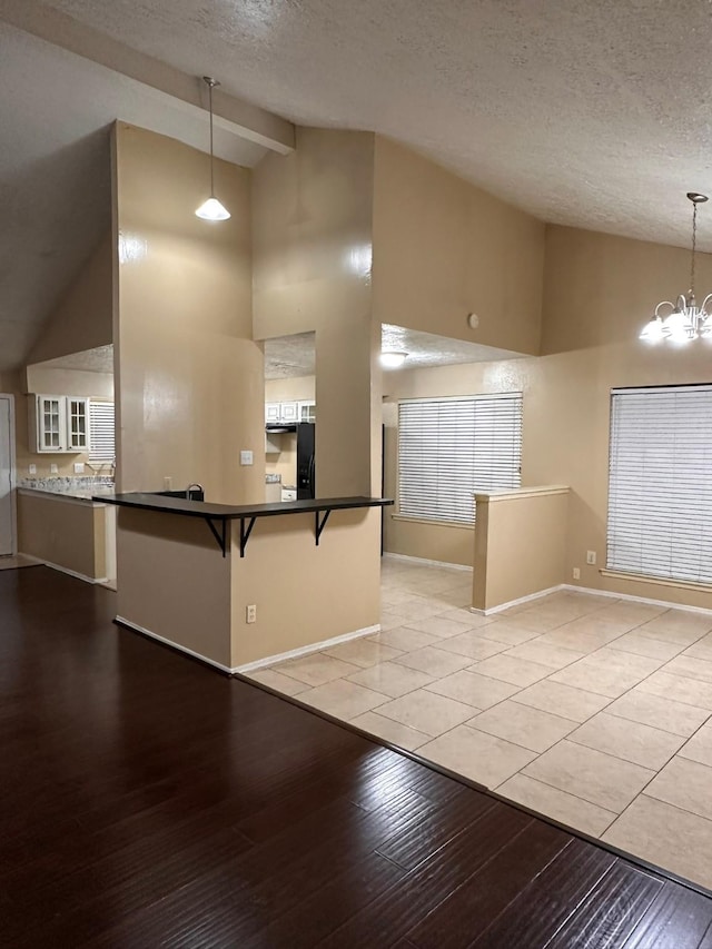 kitchen featuring a kitchen breakfast bar, light hardwood / wood-style flooring, a notable chandelier, kitchen peninsula, and pendant lighting