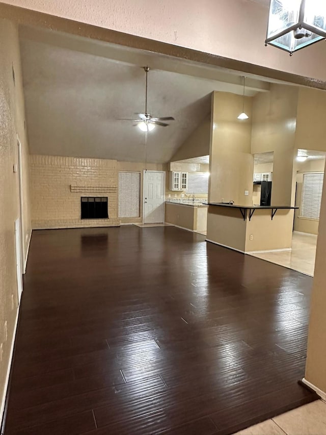 unfurnished living room featuring lofted ceiling, sink, light hardwood / wood-style flooring, a brick fireplace, and ceiling fan