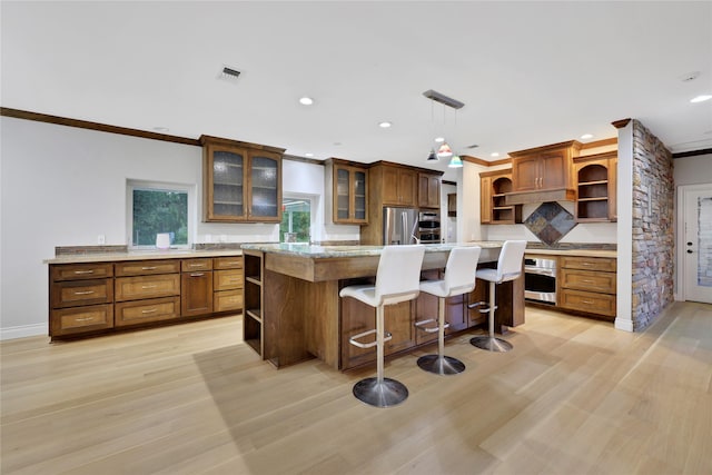 kitchen with stainless steel appliances, a kitchen island, hanging light fixtures, and light hardwood / wood-style floors