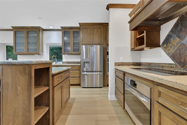 kitchen with custom range hood, stainless steel appliances, light hardwood / wood-style flooring, and light stone counters