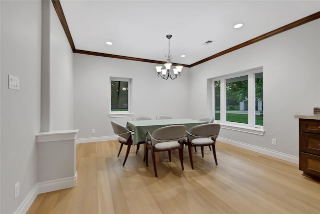 dining area with light hardwood / wood-style floors, crown molding, and an inviting chandelier