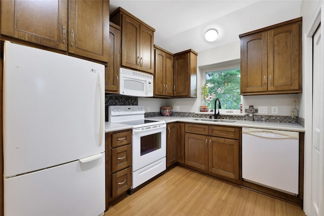 kitchen featuring backsplash, light wood-type flooring, white appliances, and sink