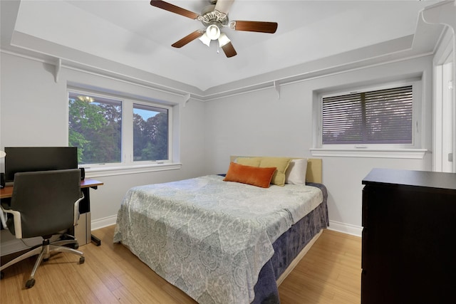 bedroom featuring light hardwood / wood-style floors, a raised ceiling, and ceiling fan